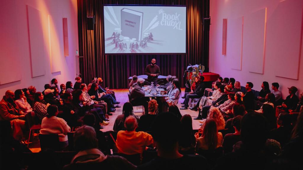 The book club gathering. In the middle of the room there is a table around which the participants have gathered.